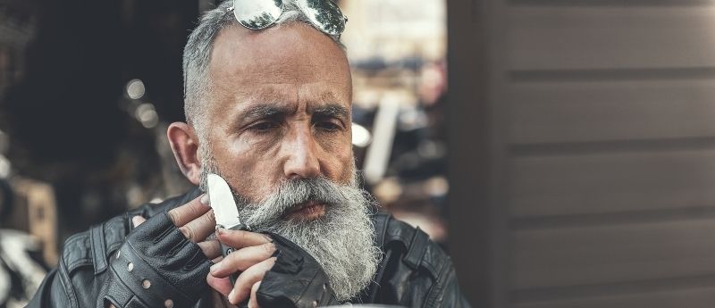 Biker with Beard shaving with knife